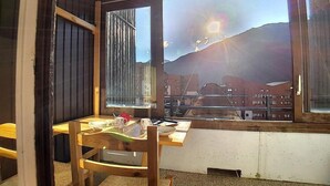 Ein Essbereich mit einem Holztisch und -stühlen, einem Fenster mit Blick auf Gebäude und einen Berg sowie einer Tür mit Holzrahmen.