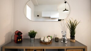 Una cocina moderna con un espejo grande, un electrodoméstico rojo, una planta en maceta, un cuenco decorativo y una pequeña figurita.