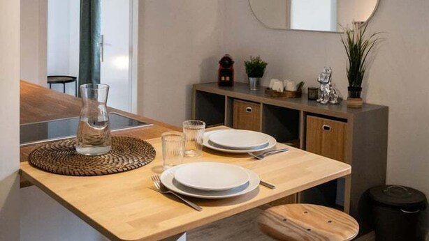 Una cocina moderna con una isla de madera, iluminación colgante, un espejo redondo y vistas al exterior.