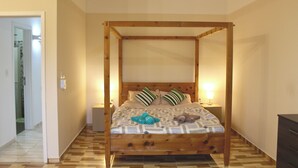 A room with a wooden four-poster bed, two bedside tables, and a wooden dresser. - Your Personal Paradise in ZenGarden: Cozy Vacation Home for Couples in Paraguay (Ñemby)