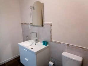 Un baño con un lavamanos blanco, un espejo encima y un inodoro.