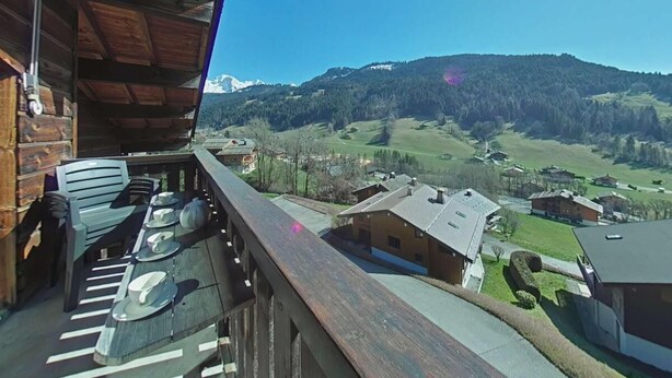 A wooden balcony with a view of a mountainous landscape and several buildings. - 3rd floor, view village, balcony, fireplace or stove, tv, 49m², Le Grand Bornand (Le Grand-Bornand)