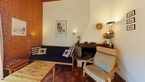 A cozy living room with a wooden ceiling, a sofa, a chair, a coffee table, and a fireplace. - 3rd floor, view village, balcony, fireplace or stove, tv, 49m², Le Grand Bornand (Le Grand-Bornand)