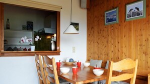 A wooden dining table with chairs, a hanging light, and a window with a view of the kitchen. - 3rd floor, view village, balcony, fireplace or stove, tv, 49m², Le Grand Bornand (Le Grand-Bornand)