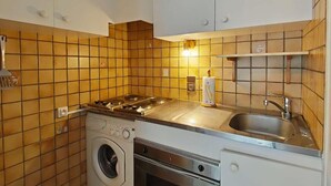 Een kleine keuken met een ingebouwde wasmachine, een fornuis en een spoelbak.