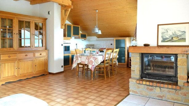 Un'ampia cucina con mobili in legno, un tavolo da pranzo per quattro persone e un camino in pietra.