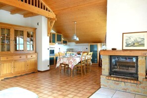 A spacious kitchen with wooden cabinets, a dining table set for four, and a stone fireplace.