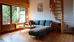 Un accogliente soggiorno con una scala in legno, un'ampia finestra e un divano.