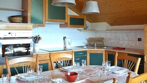 Una cucina con mobili in legno, un piano cottura e un tavolo da pranzo apparecchiato per quattro persone.