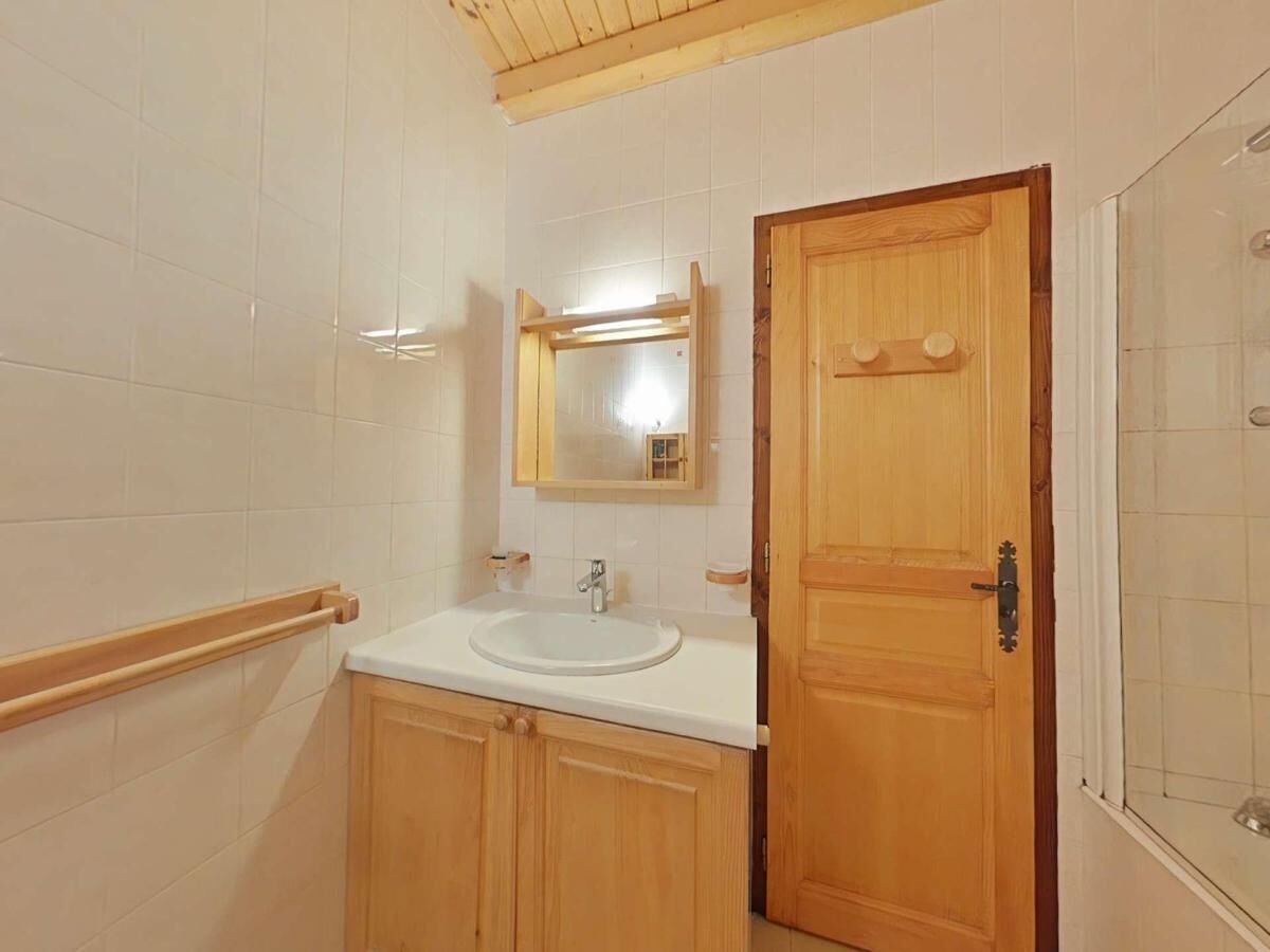 A bathroom with a wooden door, a white sink, and a mirror above it.