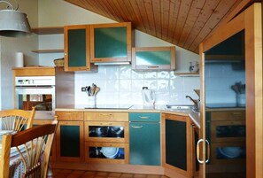 Compact kitchen with modern design, featuring a stainless steel oven, dishwasher, and ample utensils.