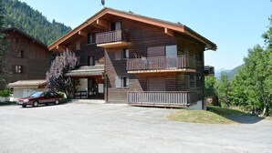 Ein zweistöckiges Holzhaus mit Balkonen und einer Garage, voran ein Auto parkt.