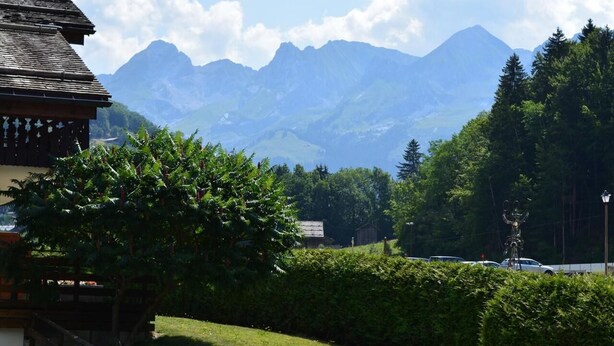 Blick auf Berge mit einem Gebäude im Vordergrund und blauem Himmel.