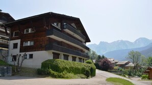 Ein mehrstöckiges Holzgebäude mit Balkonen vor einer Bergkulisse.
