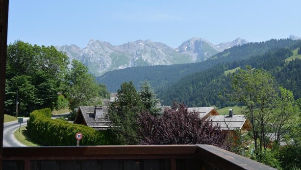 Bergblick mit Geschwindigkeitsbegrenzung 30 km/h, Häusern und einer kurvenreichen Straße durch eine grüne Landschaft.