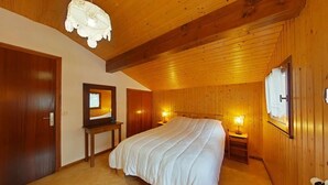 Une chambre avec un plafond en bois, un grand lit, des tables de chevet avec des lampes et une armoire en bois.
