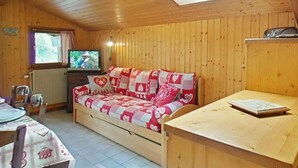 Une chaleureuse cabane en bois avec un canapé, une table à manger et un téléviseur.