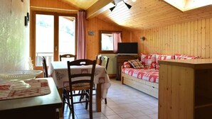 Une charmante cabane en bois avec un coin repas, un canapé et un téléviseur.