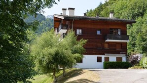 A multi-story wooden house with balconies, surrounded by greenery and mountains. - Ground floor, balcony, tv, 44m², Le Grand Bornand (Le Grand-Bornand)