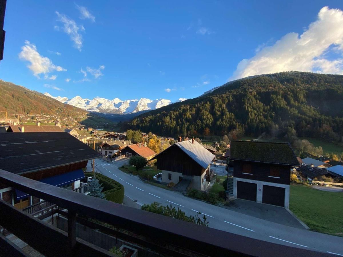 Un village de montagne avec des maisons, une route et une vue sur des montagnes enneigées.