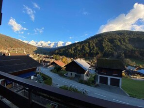 A mountain village with houses, a road, and a view of snow-capped mountains.