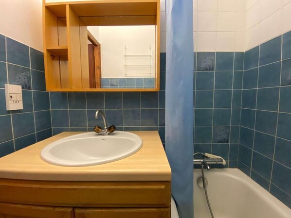 A bathroom with a sink, mirror, and bathtub.