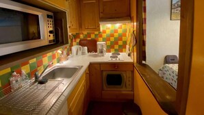 A compact kitchen with wooden cabinets, a microwave, a sink, and a small oven. - 3rd floor, view mountain, balcony, tv, 41m², Le Grand Bornand (Le Grand-Bornand)