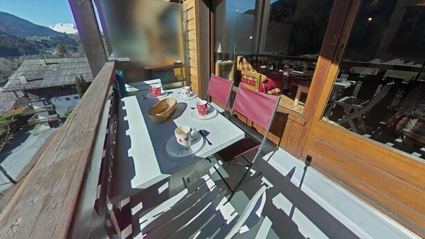 A balcony with a table set for two, a chair, and a view of a mountainous landscape. - 3rd floor, view mountain, balcony, tv, 41m², Le Grand Bornand (Le Grand-Bornand)