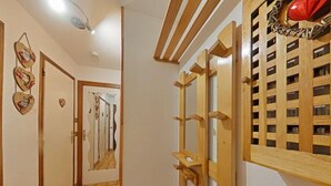 Un corridoio con pavimento in legno, una porta con specchio e una mensola a parete.