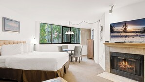 Una habitación de hotel con cama, una mesa de comedor, sillas, un televisor y una chimenea.
