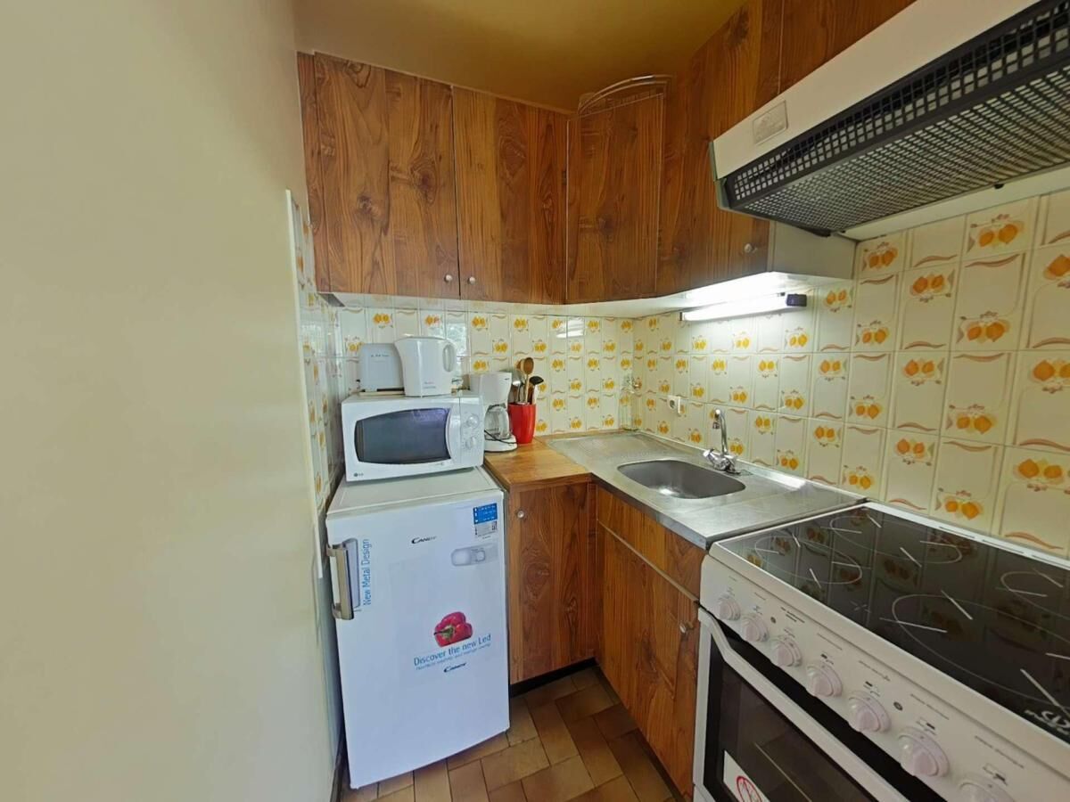 Una cucina compatta con mobili in legno, un forno a microonde, un piano cottura e un lavandino.