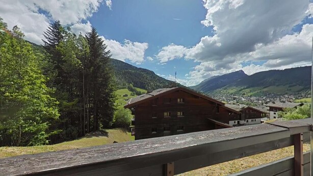 A wooden cabin with a balcony, surrounded by lush greenery and mountains in the background. - Ground floor, balcony, tv, 22m², Le Grand Bornand (Le Grand-Bornand)