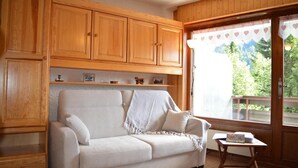 A cozy room with a white sofa, wooden cabinets, and a small table with a book. - Ground floor, balcony, tv, 22m², Le Grand Bornand (Le Grand-Bornand)