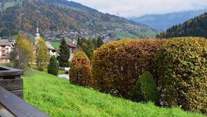 A scenic view of a town nestled in a valley with a prominent arch bridge, surrounded by lush greenery and mountains in the background.