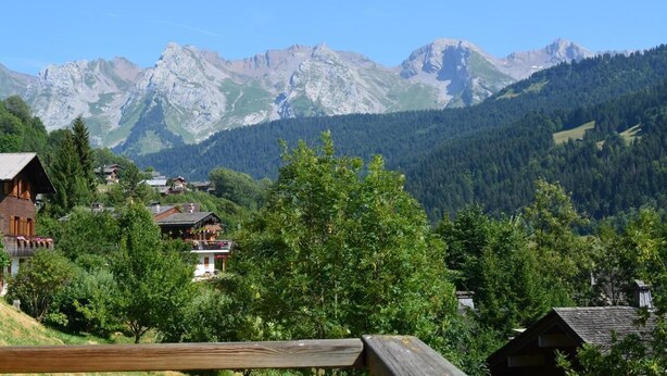 A mountain village with traditional wooden houses, a wooden fence, and a backdrop of rugged mountains. - Floor -1, view mountain, balcony, fireplace or stove, tv, 56m², Le Grand Bornand (Le Grand-Bornand)