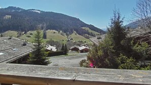 A view of a mountainous area with houses and a wooden deck in the foreground. - Floor -1, view mountain, balcony, fireplace or stove, tv, 56m², Le Grand Bornand (Le Grand-Bornand)