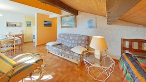 Una habitación acogedora con techo de madera, un sofá, una cama y un comedor.