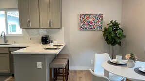 Una cocina moderna con una isla central, taburetes de madera y una mesa de comedor con sillas blancas.