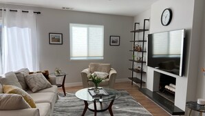 Una sala de estar moderna con sofá, sillón, mesa de centro y televisión montada en la pared.