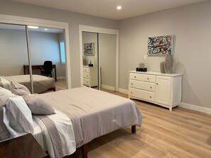 Une chambre à coucher avec un lit, une commode, un miroir et un tableau accroché au mur.