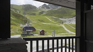 A mountain view from a covered porch with a ski lift and a small building in the foreground. - 100m from ski slopes, 2nd floor, view ski slopes, jacuzzi, hammam, parking, tv, ski locker, 66m² (Germ)