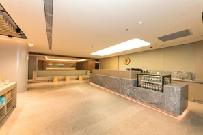 Un moderno vestíbulo de hotel con mostrador de recepción, zona de estar y una escalera.