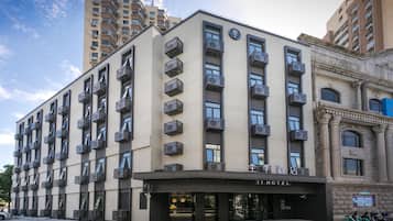 A hotel with multiple floors, air conditioning units, and a sign indicating it's a hotel.