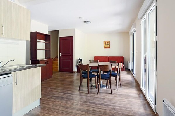 A modern kitchen with wooden cabinets and a dining area with a table and chairs.