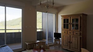 Ein Schlafzimmer mit großem Fenster, einer Kristallleuchtre, einem Holzschrank und einem Fernseher auf einem kleinen Tisch.