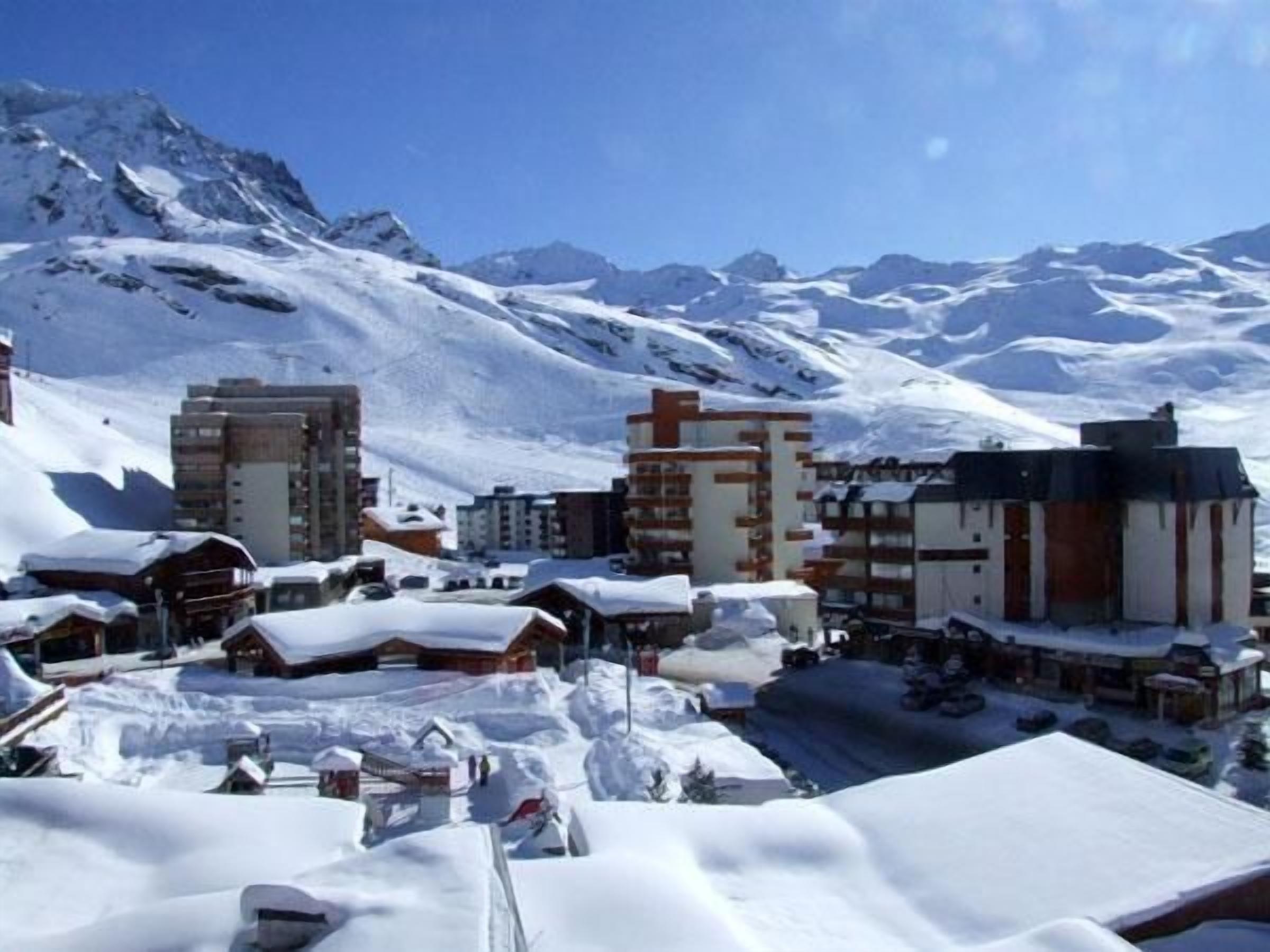 A snow-covered town with buildings and a mountain backdrop.
