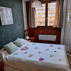 A bedroom with a bed, a chair, a radiator, and a window with curtains. - 200m from ski slopes, 7th floor, balcony, tv, 35m², Val Thorens (Val Thorens)