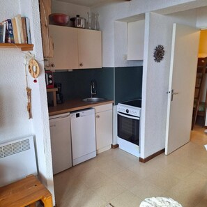 A compact kitchen with white cabinets, a built-in oven, and a sink.