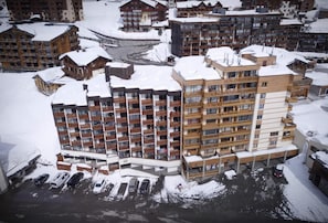A multi-story hotel with balconies, a parking area, and snow-covered surroundings. - 200m from ski slopes, 7th floor, balcony, tv, 35m², Val Thorens (Val Thorens)