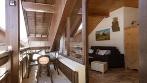 A wooden interior with a dining area, a sofa, and a painting on the wall.